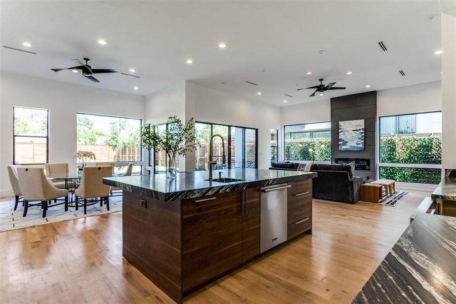 Kitchen featuring a spacious island, a wealth of natural light, light wood-type flooring, and sink