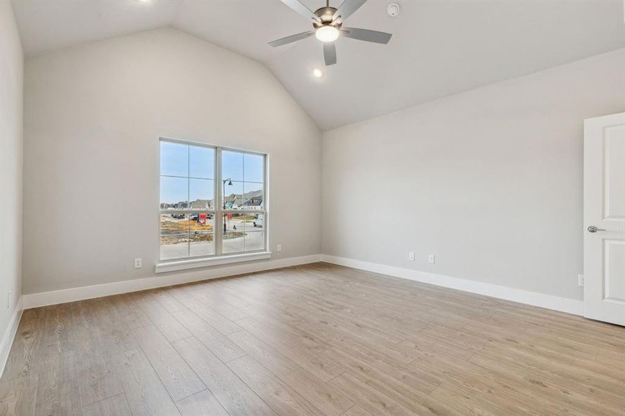 Empty room with high vaulted ceiling, ceiling fan, and light hardwood / wood-style floors