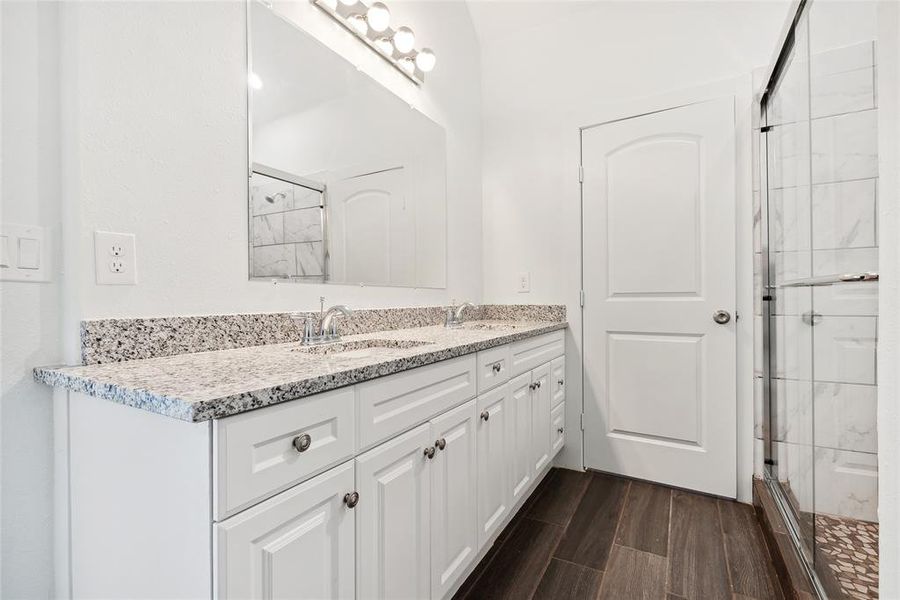 Bathroom with hardwood / wood-style floors, a shower with door, and vanity