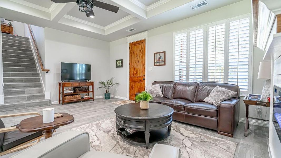 Living room featuring a healthy amount of sunlight, beamed ceiling, coffered ceiling, and ceiling fan