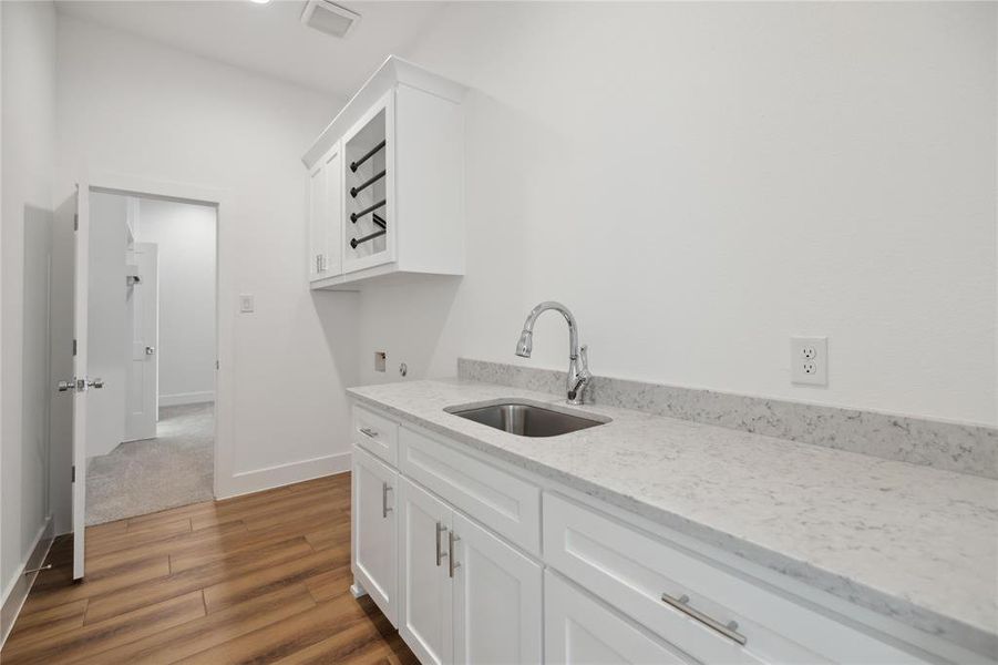 Kitchen featuring white cabinets, light stone countertops, sink, and dark hardwood / wood-style flooring