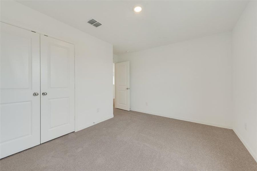 Unfurnished bedroom with light carpet and a closet