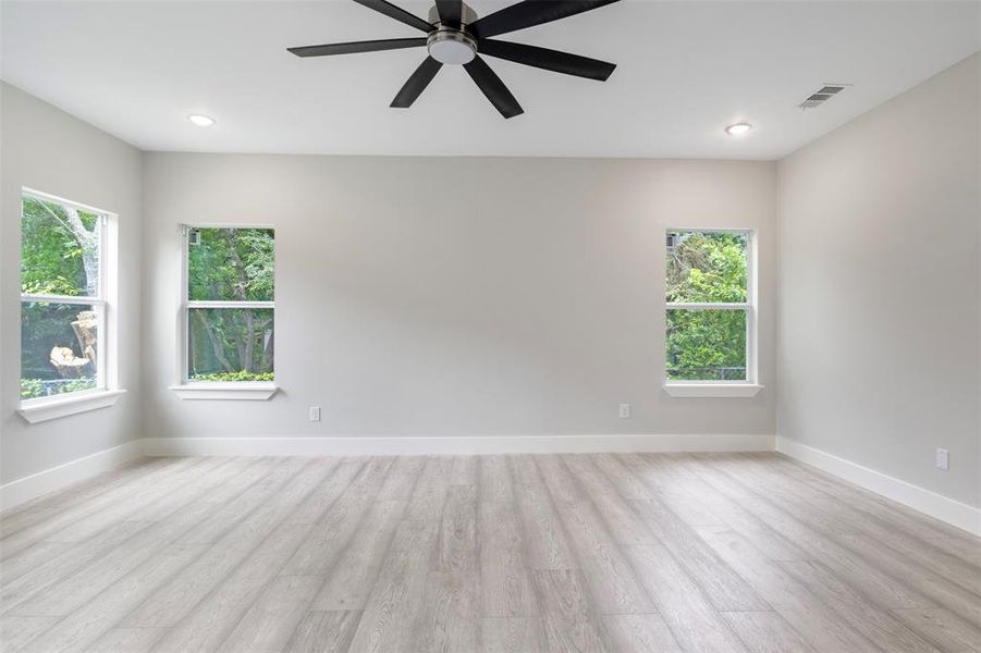 Spare room featuring plenty of natural light, ceiling fan, and light wood-type flooring