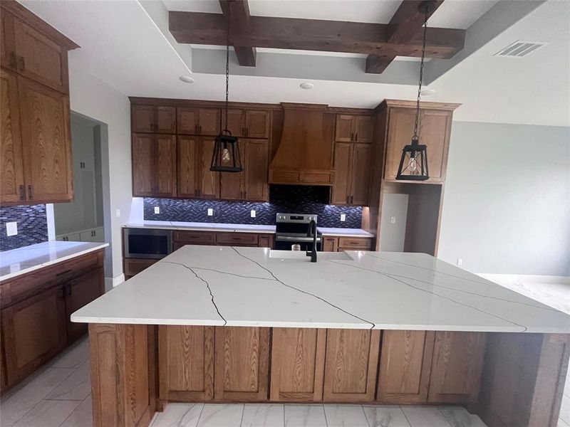 Kitchen with a large island with sink, beam ceiling, pendant lighting, premium range hood, and tasteful backsplash