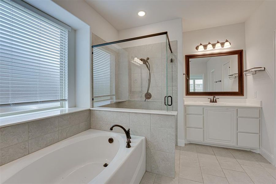 Bathroom featuring a wealth of natural light, vanity, plus walk in shower, and tile patterned floors