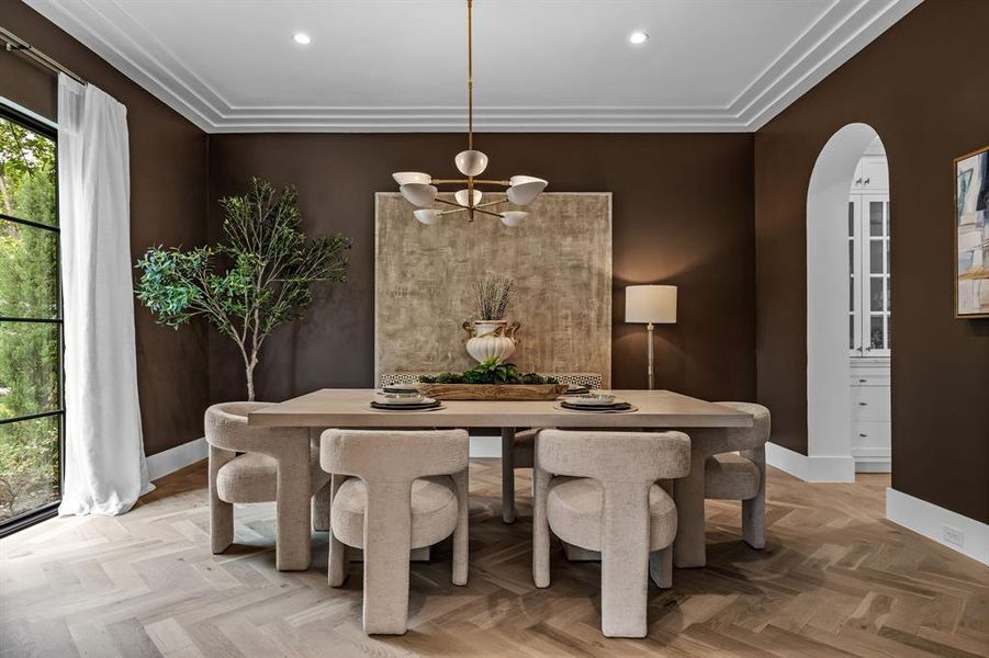 Dining room with ornamental molding, light parquet flooring, and a chandelier