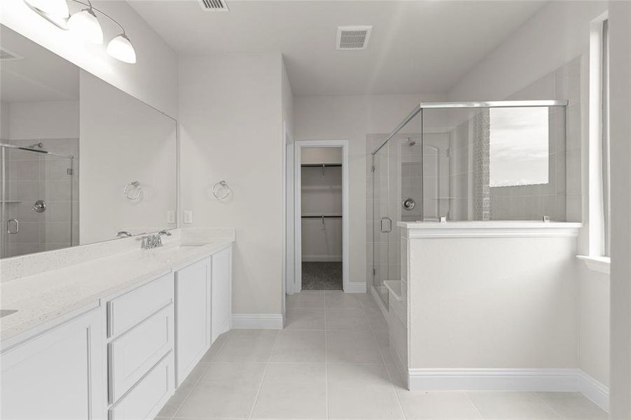 Bathroom featuring a shower with shower door, tile flooring, and vanity