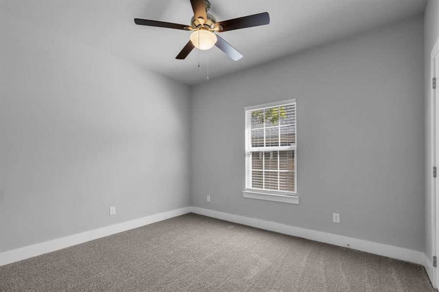 Carpeted empty room featuring ceiling fan