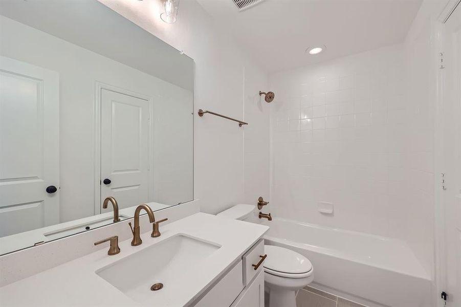 Full bathroom with tiled shower / bath, vanity, toilet, and tile patterned floors