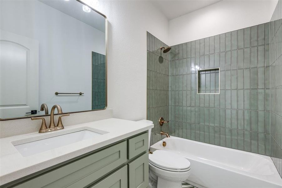 Full bathroom with tiled shower / bath combo, vanity, and toilet