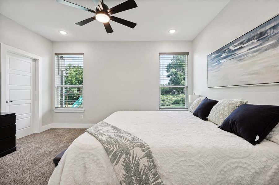 Bedroom featuring carpet flooring, multiple windows, and ceiling fan