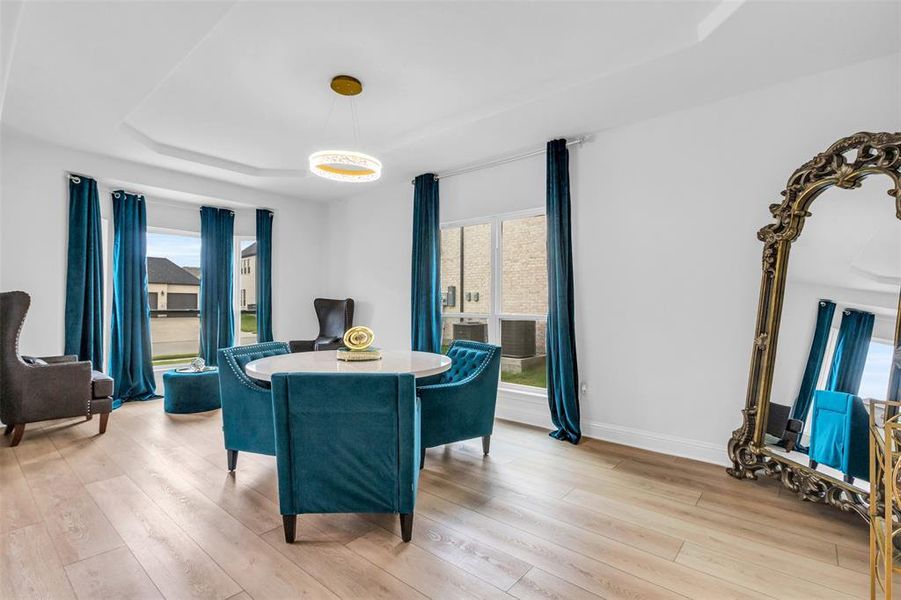 Dining area featuring a raised ceiling and light wood-type flooring