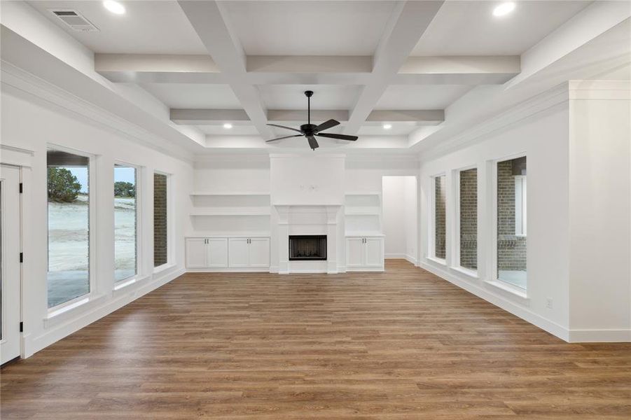 Unfurnished living room featuring beamed ceiling, light hardwood / wood-style floors, coffered ceiling, and ceiling fan