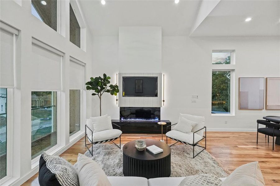 Living room with a towering ceiling and light hardwood / wood-style flooring