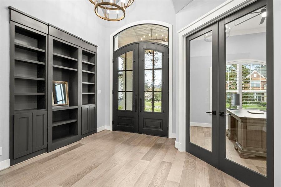 Stunning 11ft iron doors with privacy glass lead to a stately entryway with chandelier, groin ceiling, custom built-in bookshelves and a double glass door entry to the office