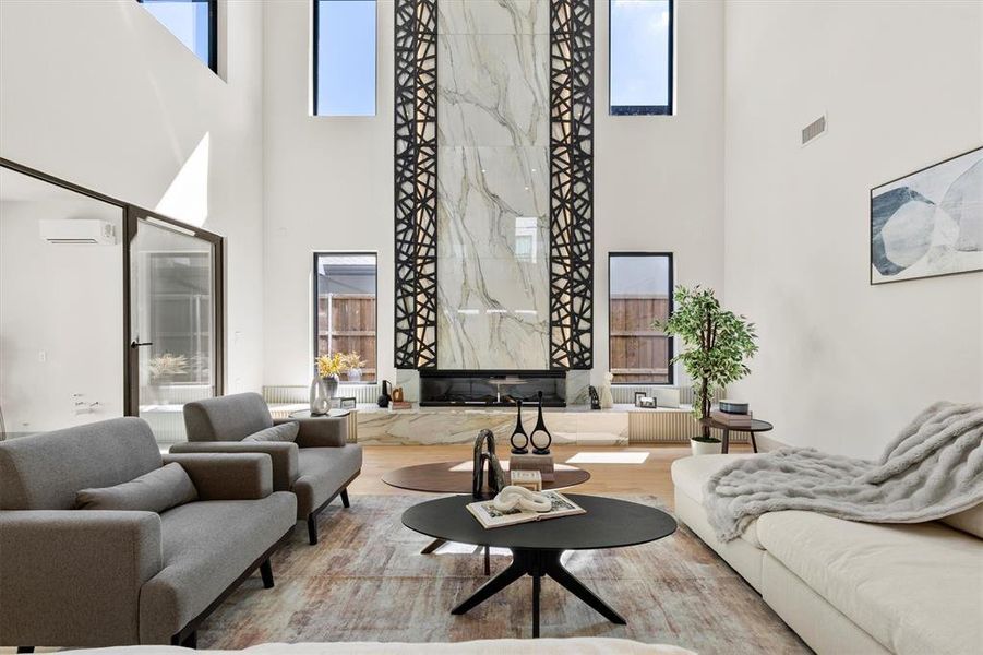 Living room with an AC wall unit, a towering ceiling, and hardwood / wood-style flooring