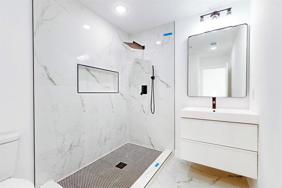 Bathroom with a tile shower, vanity, and toilet