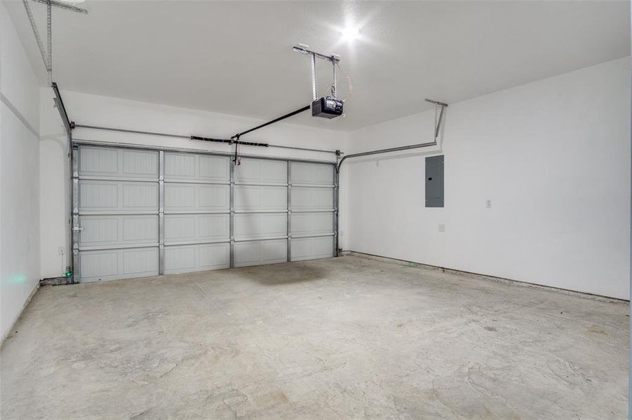 Garage featuring a garage door opener and electric panel