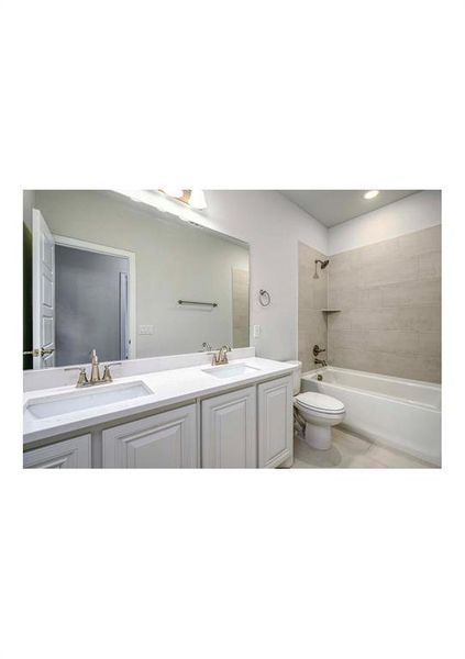 Full bathroom featuring vanity, tiled shower / bath combo, toilet, and tile patterned flooring