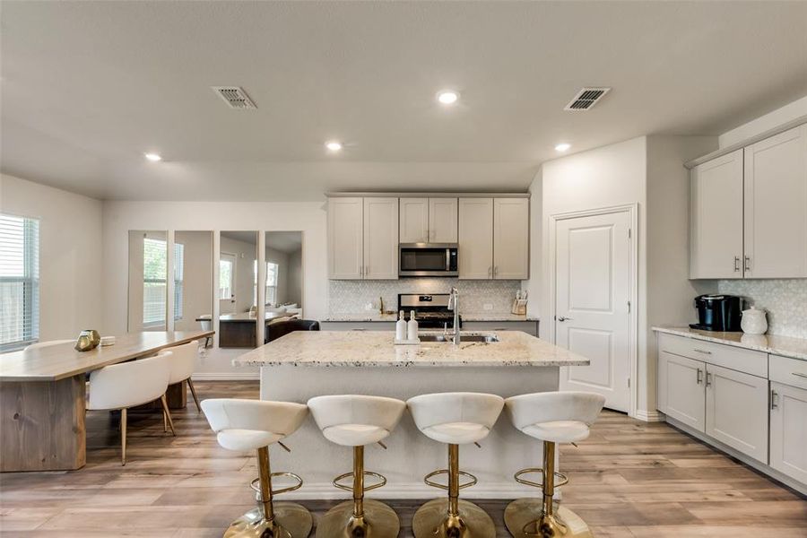 Kitchen with backsplash, appliances with stainless steel finishes, sink, and light wood-type flooring