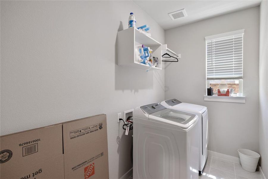 Washroom featuring light tile patterned flooring and washer and clothes dryer