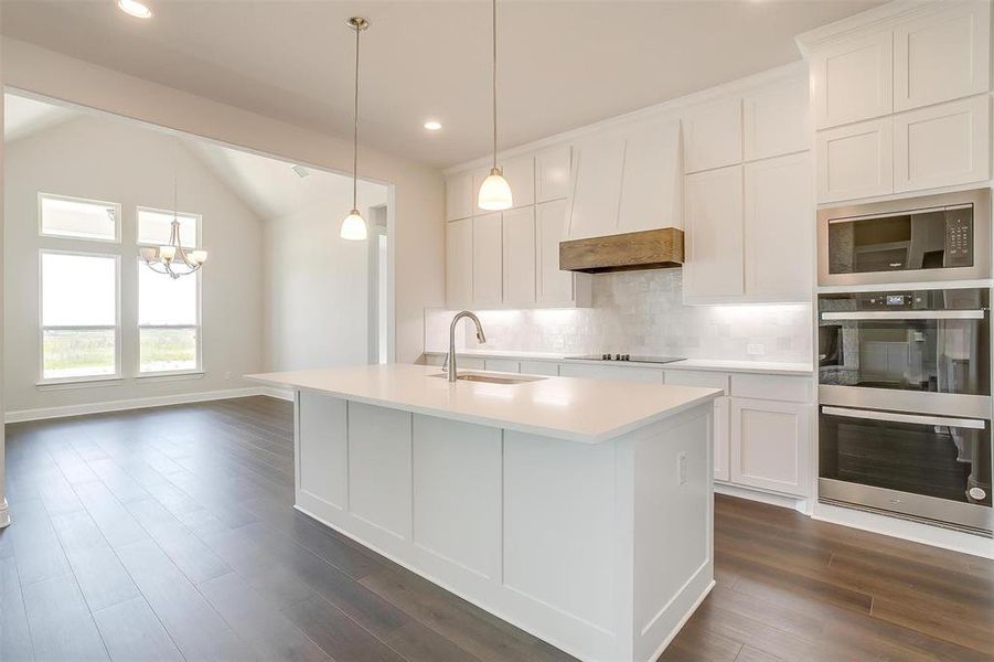 Kitchen with black appliances, decorative backsplash, custom range hood, lofted ceiling, and dark wood-type flooring