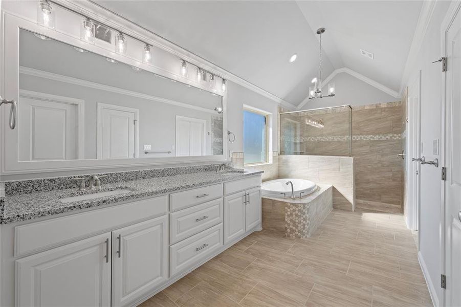 Bathroom with plus walk in shower, vaulted ceiling, vanity, crown molding, and an inviting chandelier