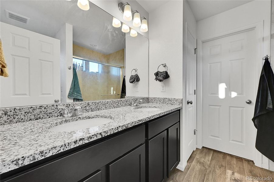 The private en-suite bathroom offers laminate flororing, a large double vanity with plenty of cabinetry, a spacious shower and easy access to the walk-in closet.