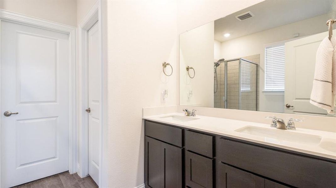 Bathroom featuring wood-type flooring, double sink vanity, and an enclosed shower