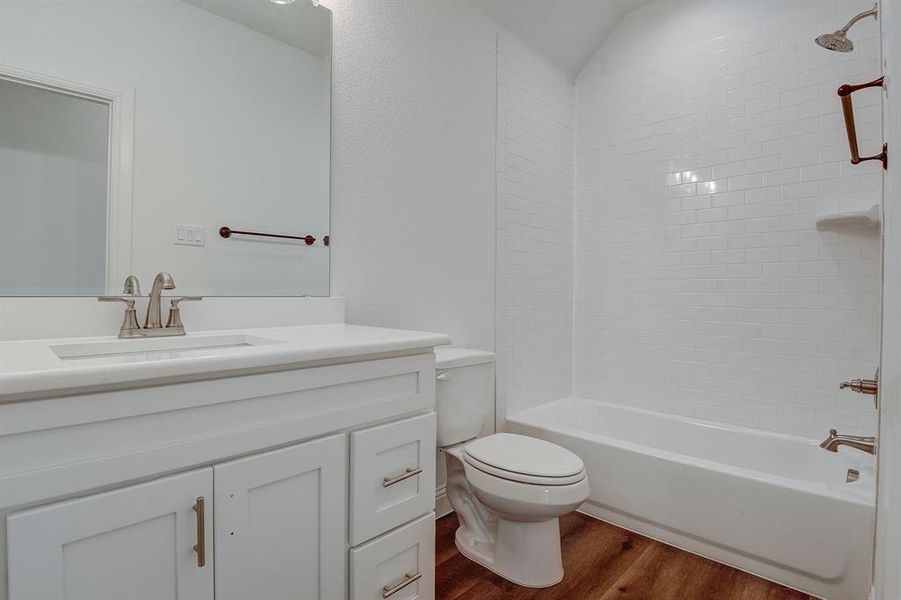 Full bathroom featuring wood-type flooring, vanity, toilet, and tiled shower / bath combo