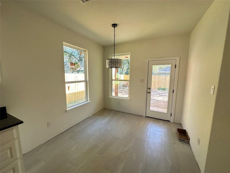 Unfurnished dining area featuring a textured ceiling, a healthy amount of sunlight, and a chandelier