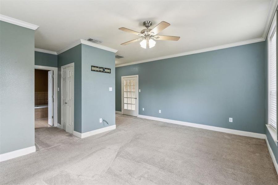 Master bedroom with light carpet, ensuite bath, crown molding, and ceiling fan