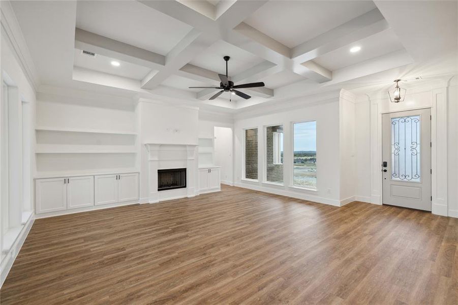 Unfurnished living room with hardwood / wood-style floors, built in features, coffered ceiling, and ceiling fan