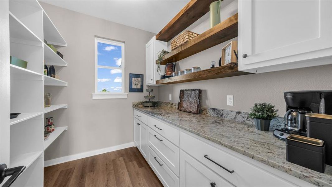 Kitchen with light stone countertops, dark wood-type flooring, and white cabinets