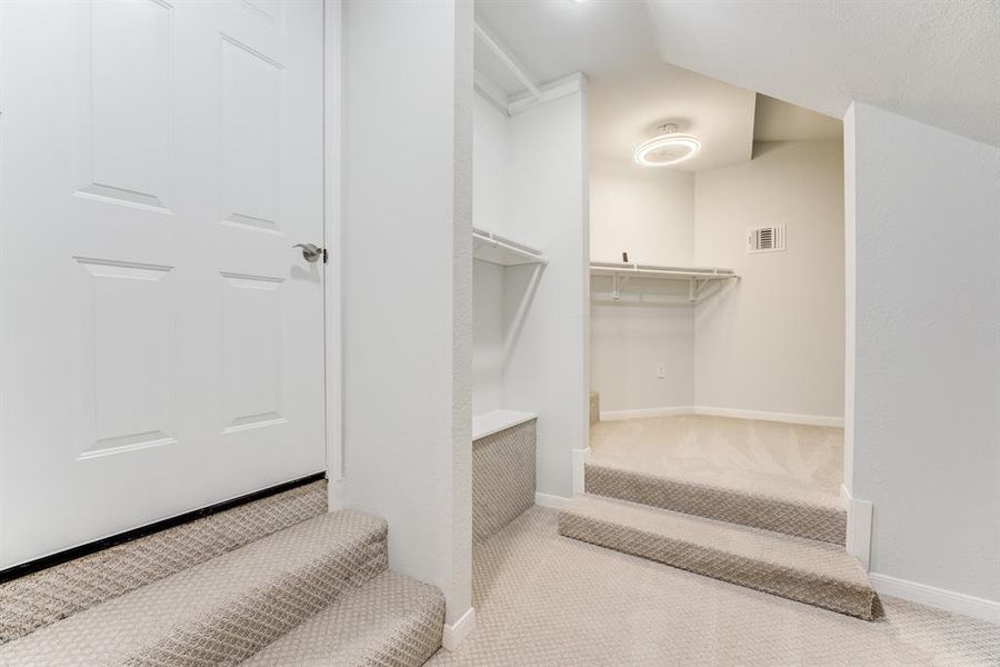 This is a neat, carpeted walk-in closet with built-in shelves, ideal for organized storage.