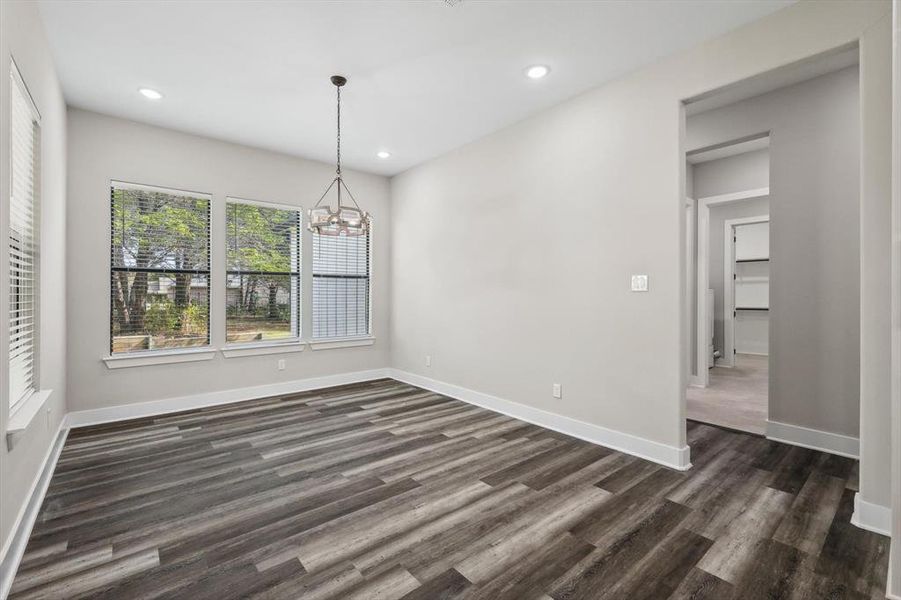 Unfurnished dining area featuring a notable chandelier and dark hardwood / wood-style floors