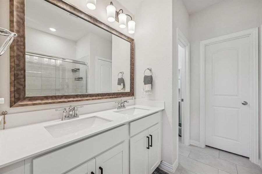 Bathroom with vanity, a shower with shower door, and tile patterned flooring