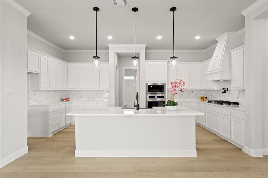 Kitchen with backsplash, light hardwood / wood-style floors, an island with sink, and white cabinets