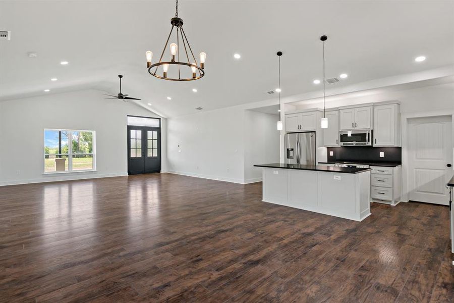 Kitchen with white cabinets, dark hardwood / wood-style floors, hanging light fixtures, and appliances with stainless steel finishes