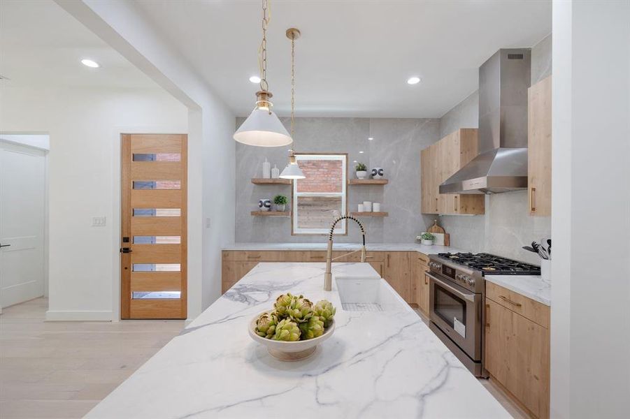 Upon entering through this modern glass and white oak door, you are greeted by a designer kitchen.  This kitchen features waterfall quartz counters, white oak cabinetry, brass fixtures, and ceiling height book matched back splash.