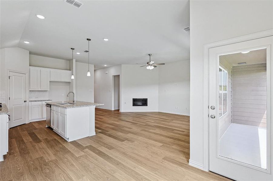 Kitchen with sink, light stone countertops, an island with sink, and light hardwood / wood-style flooring