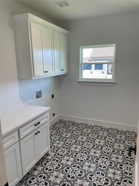 Clothes washing area featuring hookup for an electric dryer, cabinets, and washer hookup