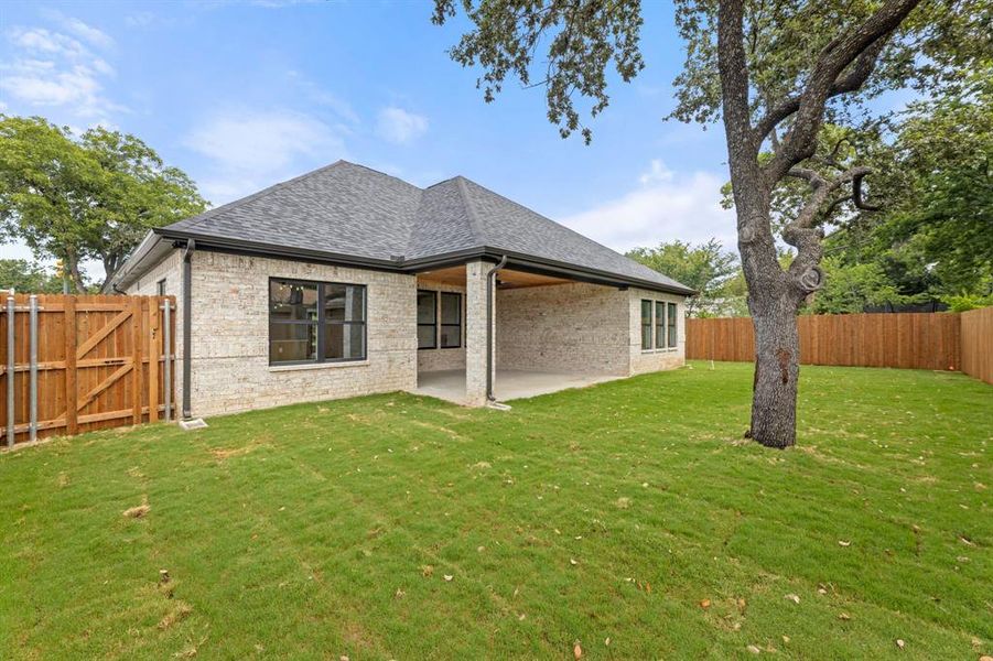 Rear view of house featuring a patio and a lawn