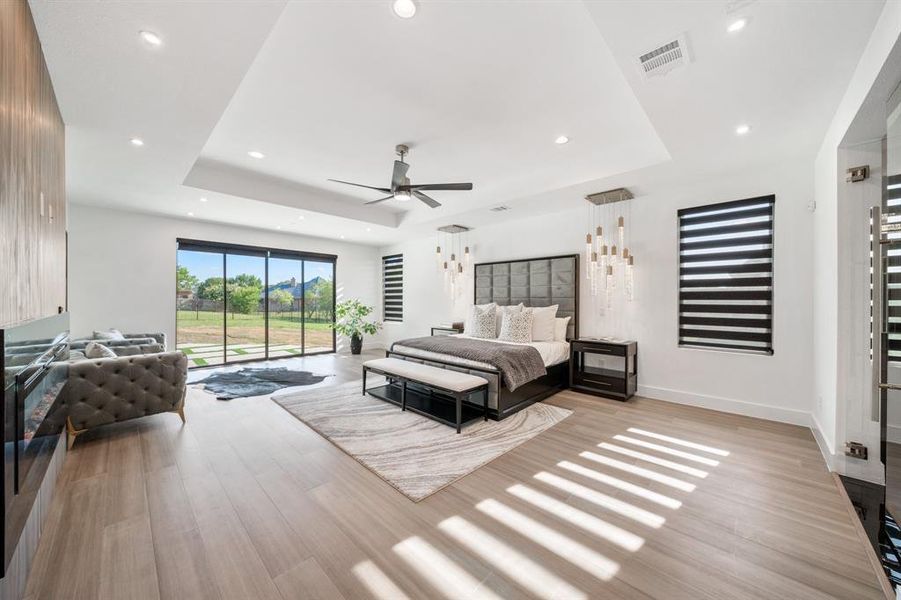 Bedroom featuring access to exterior, light hardwood / wood-style flooring, and a raised ceiling