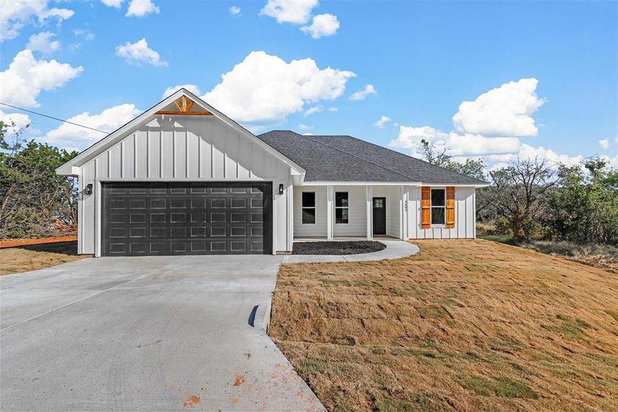 Modern farmhouse style home featuring a front yard and a garage