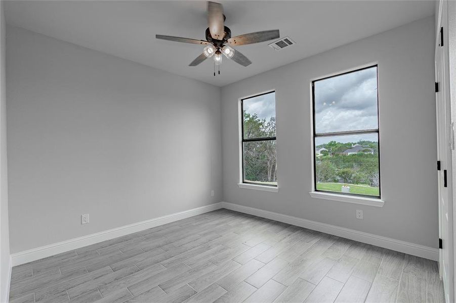 Empty room with light hardwood / wood-style floors, a wealth of natural light, and ceiling fan