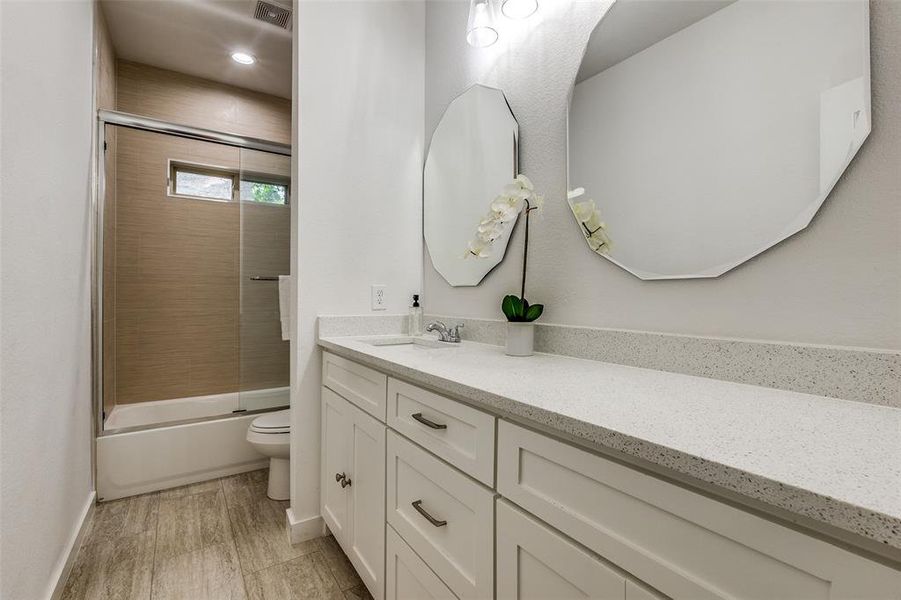 Full bathroom featuring tiled shower / bath combo, toilet, and vanity