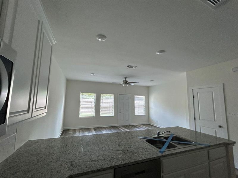 Kitchen with hardwood / wood-style flooring, white cabinets, dishwashing machine, sink, and ceiling fan