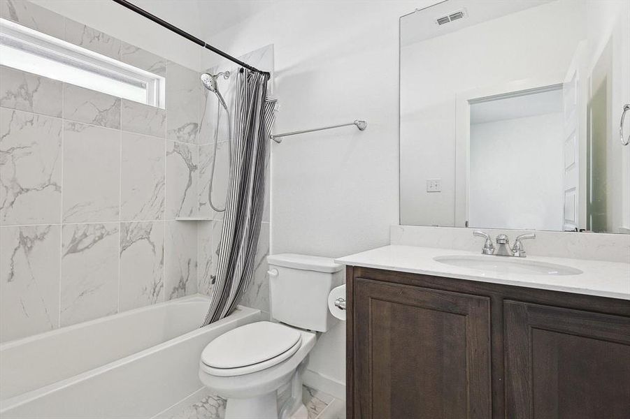 Full bathroom featuring toilet, shower / bath combo, and vanity