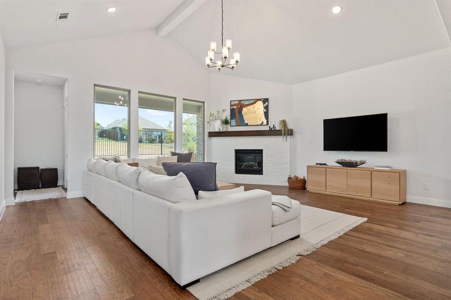 Living room featuring a notable chandelier, beam ceiling, dark hardwood / wood-style flooring, and a fireplace